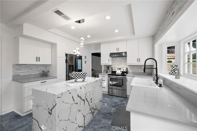 kitchen with sink, appliances with stainless steel finishes, white cabinetry, decorative light fixtures, and a raised ceiling