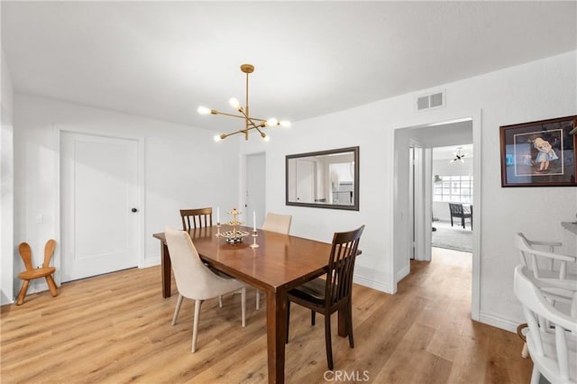 dining space with an inviting chandelier and light hardwood / wood-style flooring