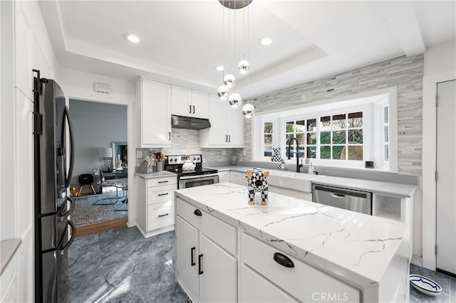 kitchen featuring appliances with stainless steel finishes, white cabinetry, a kitchen island, decorative light fixtures, and a raised ceiling