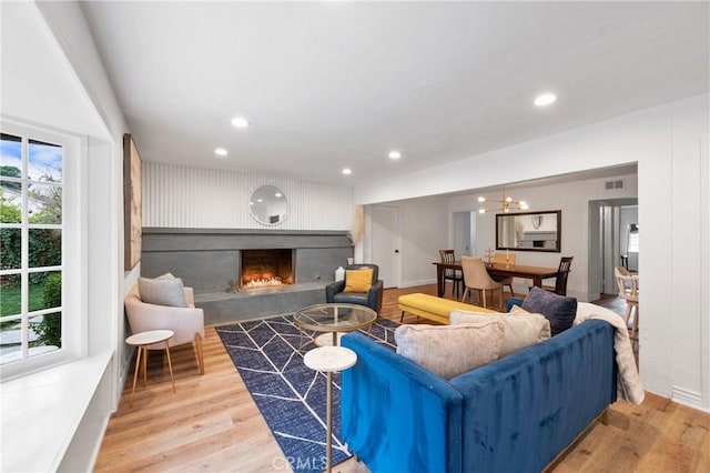 living room featuring a wealth of natural light, light hardwood / wood-style floors, and a large fireplace