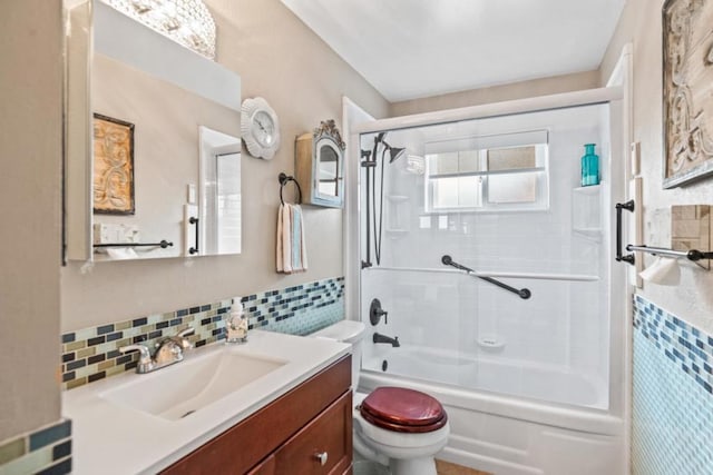 full bathroom with tile walls, bath / shower combo with glass door, vanity, decorative backsplash, and toilet