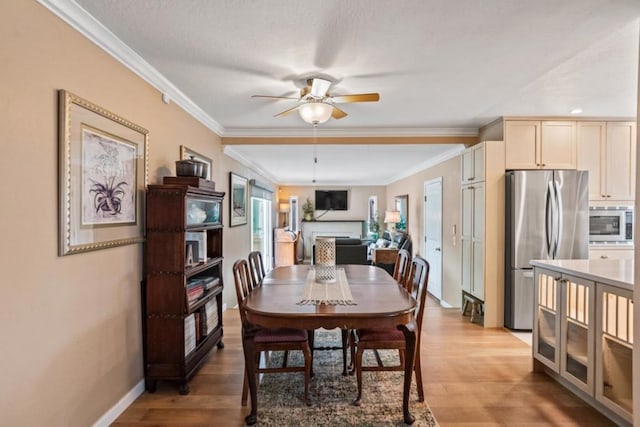 dining area featuring crown molding, ceiling fan, and light hardwood / wood-style flooring