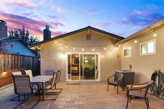 back house at dusk with cooling unit and a patio area