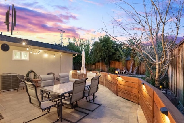 patio terrace at dusk featuring central AC unit