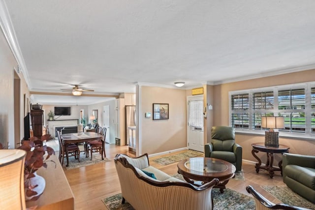 living room with crown molding, ceiling fan, and light wood-type flooring