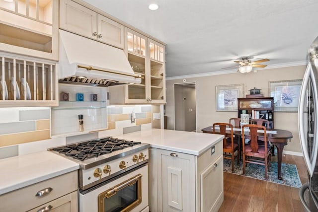 kitchen with dark wood-type flooring, ornamental molding, stainless steel appliances, and cream cabinets