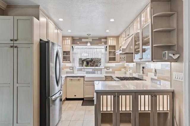 kitchen featuring sink, appliances with stainless steel finishes, range hood, decorative light fixtures, and kitchen peninsula