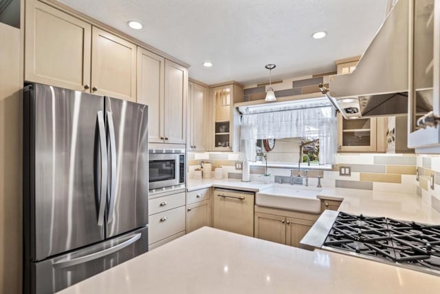 kitchen featuring sink, appliances with stainless steel finishes, decorative backsplash, exhaust hood, and light brown cabinets