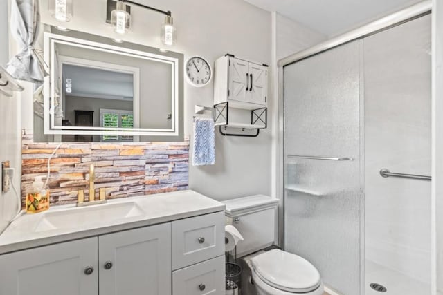 bathroom featuring a shower with door, vanity, backsplash, and toilet