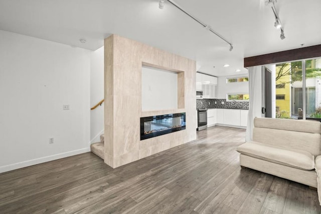 unfurnished living room featuring track lighting, a tile fireplace, and dark hardwood / wood-style floors