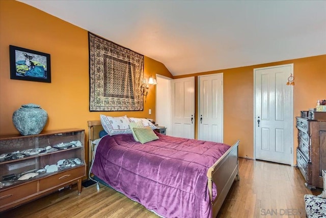 bedroom featuring lofted ceiling and light hardwood / wood-style floors