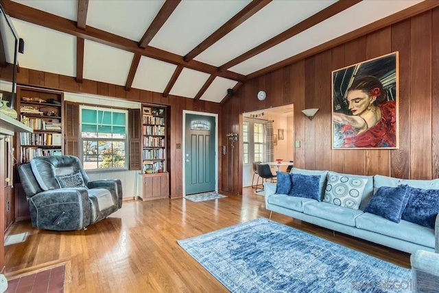 living room with wood walls, beam ceiling, light hardwood / wood-style floors, and a wealth of natural light