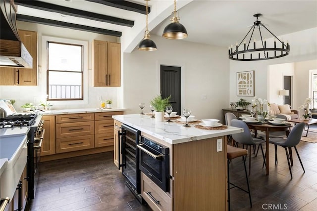 kitchen featuring high end range, hanging light fixtures, a center island, wine cooler, and extractor fan