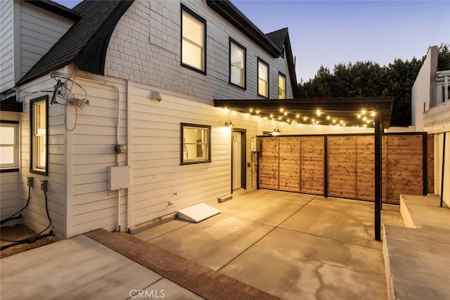 back house at dusk featuring a patio area