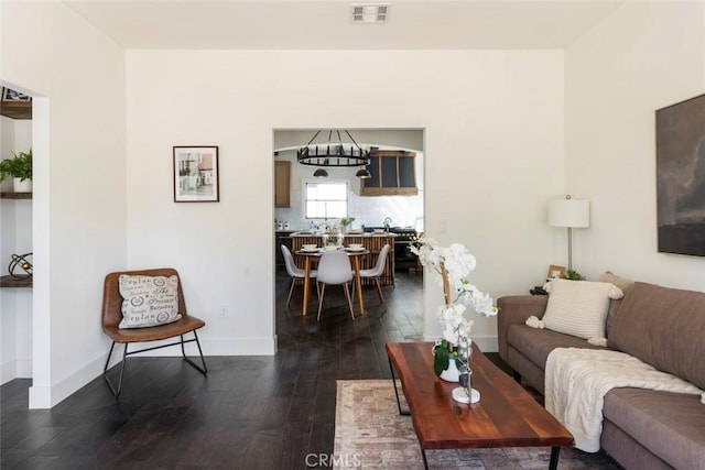 living room with a notable chandelier and dark hardwood / wood-style flooring