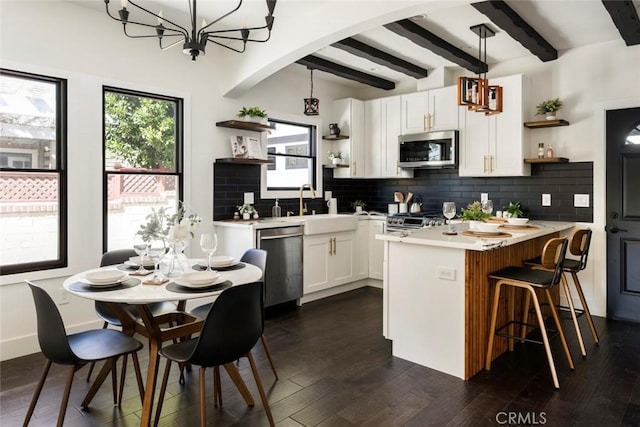 kitchen featuring sink, white cabinetry, tasteful backsplash, hanging light fixtures, and stainless steel appliances