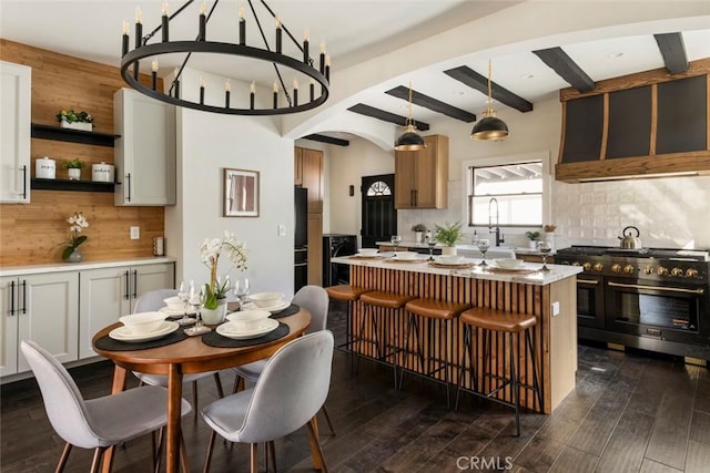 kitchen with backsplash, dark hardwood / wood-style floors, a center island, decorative light fixtures, and range with two ovens