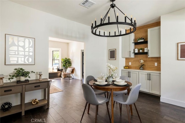 dining space with dark wood-type flooring and an inviting chandelier