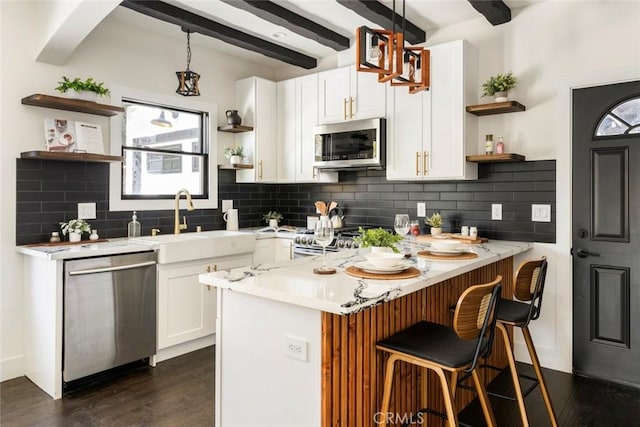 kitchen featuring appliances with stainless steel finishes, white cabinetry, sink, hanging light fixtures, and kitchen peninsula