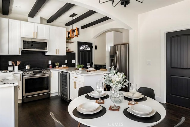 kitchen with wine cooler, hanging light fixtures, white cabinetry, and appliances with stainless steel finishes