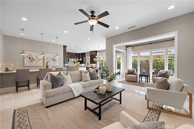 living room featuring ceiling fan with notable chandelier and light tile patterned floors