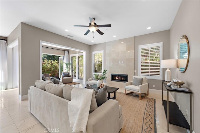 living room with a fireplace, a wealth of natural light, and ceiling fan