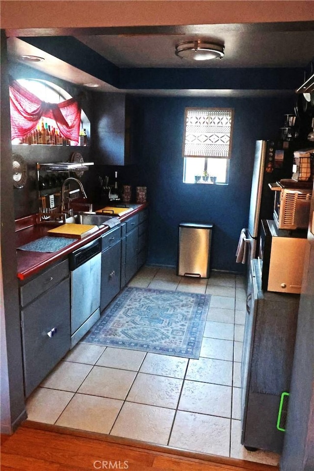 kitchen featuring dishwasher, sink, and light tile patterned floors