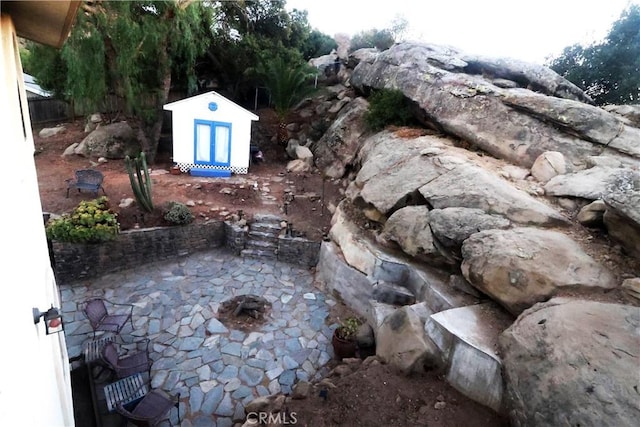 view of yard with a storage shed, a patio area, and an outdoor fire pit