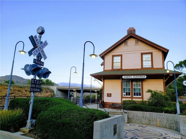 view of front of property with a chimney and fence