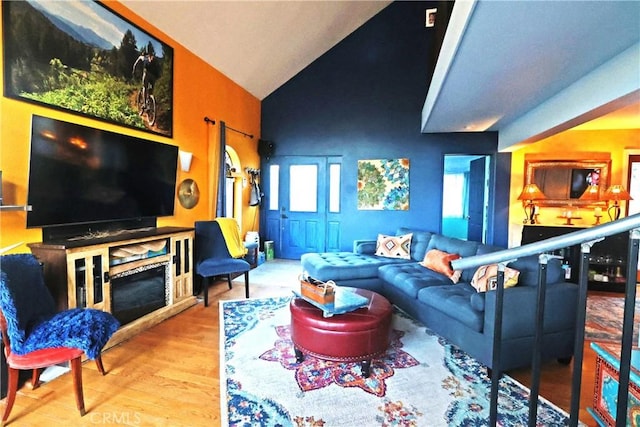 living room featuring lofted ceiling, a fireplace, and wood-type flooring