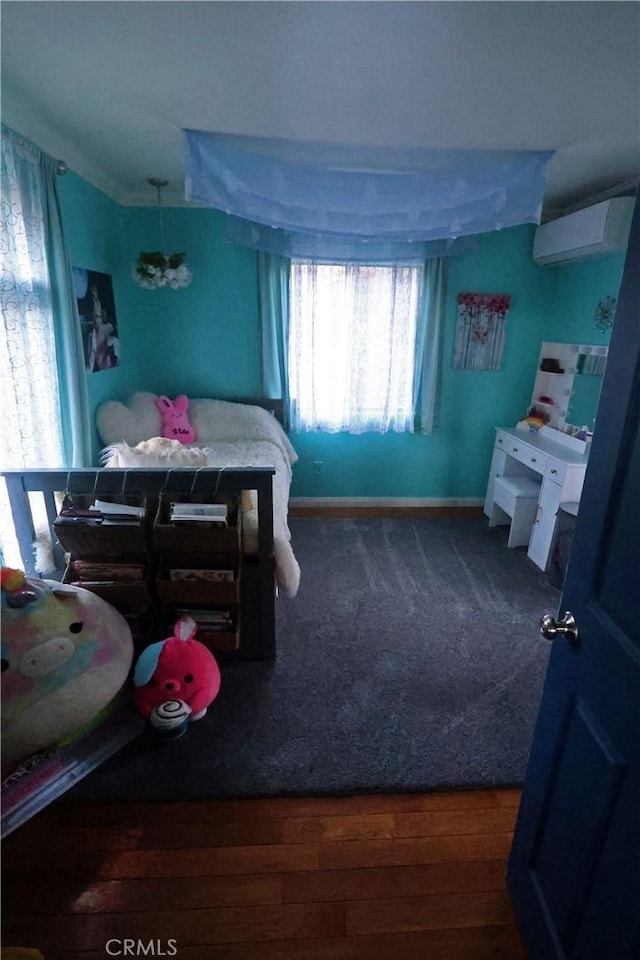 bedroom with a wall mounted AC, an inviting chandelier, and wood finished floors