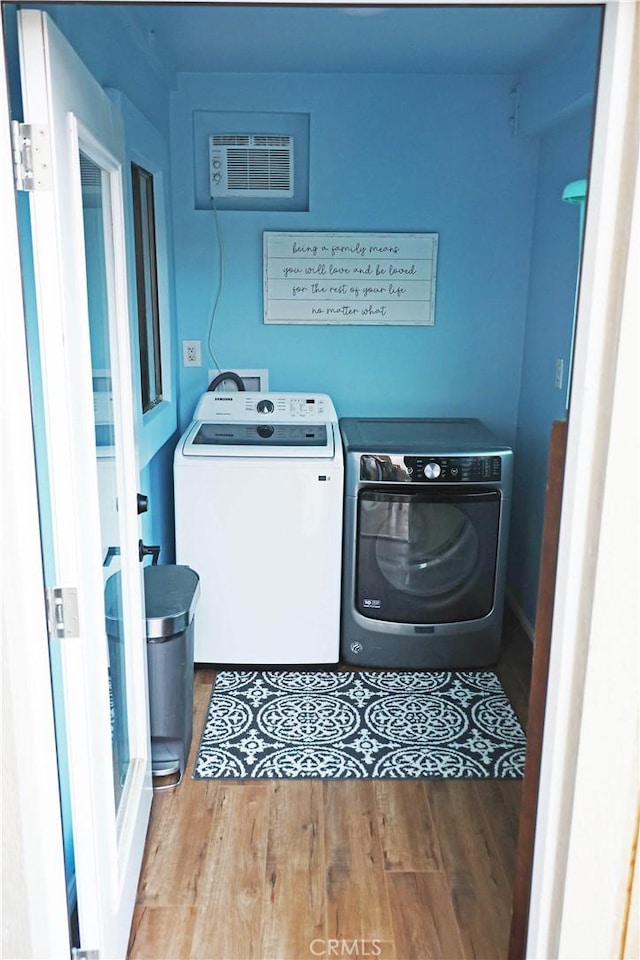 laundry area with laundry area, separate washer and dryer, and wood finished floors