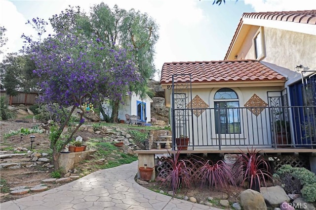 back of house featuring covered porch, stucco siding, and a tile roof