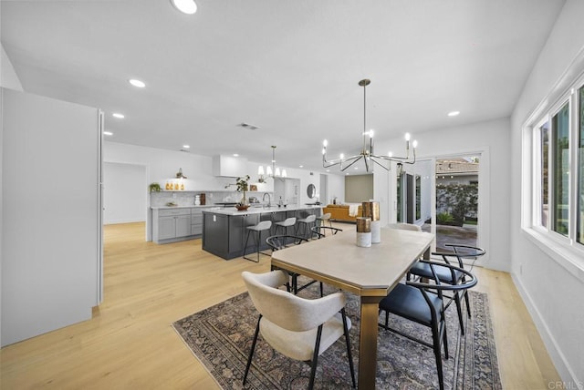 dining space with a chandelier, sink, and light hardwood / wood-style flooring