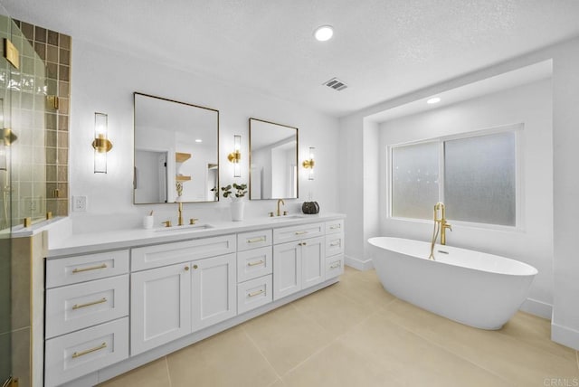 bathroom with vanity, a bath, tile patterned flooring, and a textured ceiling