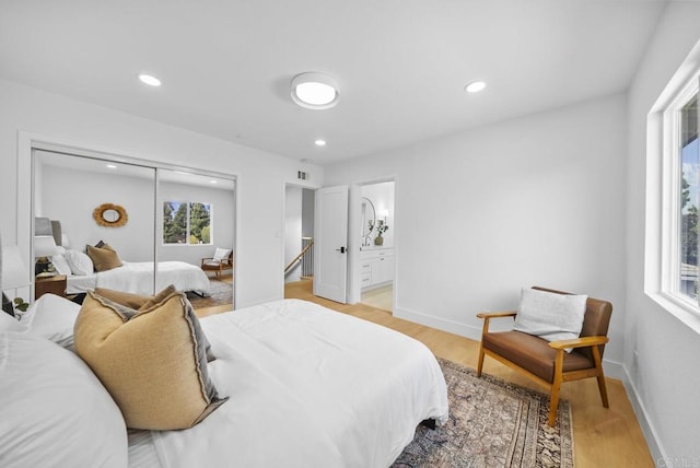 bedroom featuring ensuite bath, light hardwood / wood-style flooring, and a closet