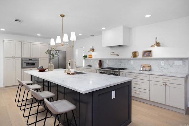 kitchen featuring a large island with sink, white cabinetry, appliances with stainless steel finishes, and sink