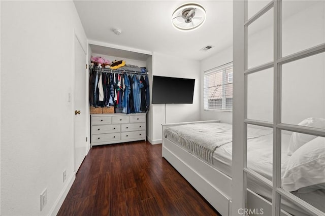 bedroom with dark hardwood / wood-style floors and a closet