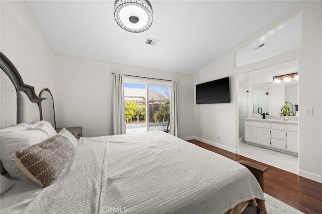 bedroom featuring connected bathroom, vaulted ceiling, access to exterior, and light wood-type flooring