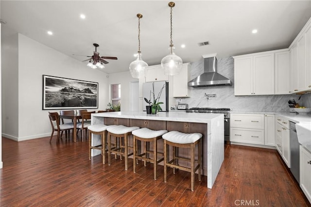 kitchen with wall chimney exhaust hood, a kitchen island, white fridge, and white cabinets