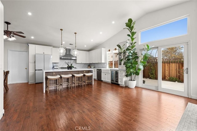 kitchen with a breakfast bar area, a center island, black dishwasher, beverage cooler, and wall chimney exhaust hood