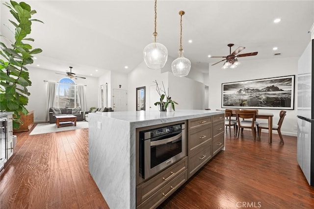 kitchen featuring stainless steel oven, dark hardwood / wood-style floors, a kitchen island, pendant lighting, and light stone countertops