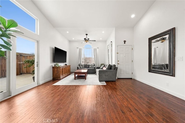 unfurnished living room with dark wood-type flooring, ceiling fan, and a towering ceiling