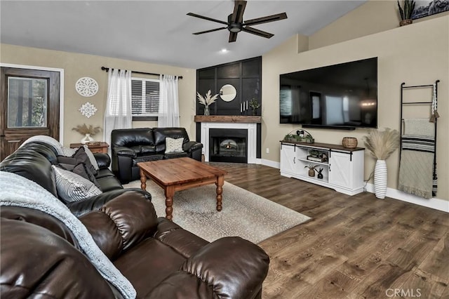 living room featuring dark hardwood / wood-style flooring, lofted ceiling, ceiling fan, and a fireplace