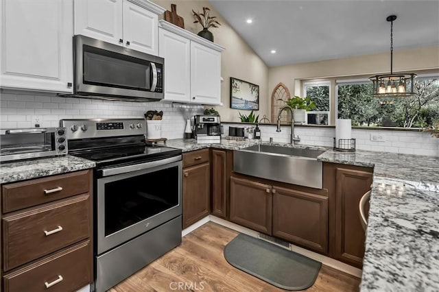 kitchen with sink, light hardwood / wood-style flooring, white cabinetry, stainless steel appliances, and vaulted ceiling