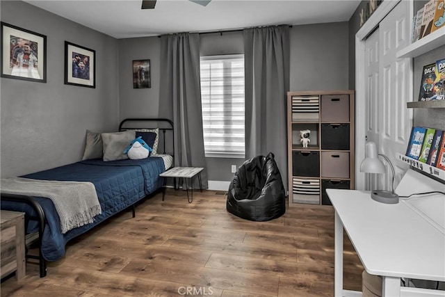 bedroom with dark hardwood / wood-style floors, ceiling fan, and a closet