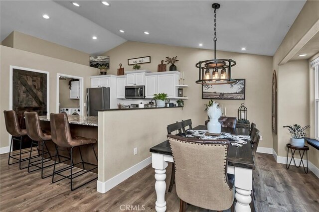 dining space featuring vaulted ceiling, dark hardwood / wood-style floors, and washing machine and dryer