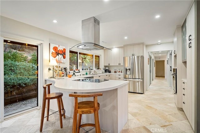 kitchen featuring white cabinetry, appliances with stainless steel finishes, a kitchen breakfast bar, kitchen peninsula, and island exhaust hood