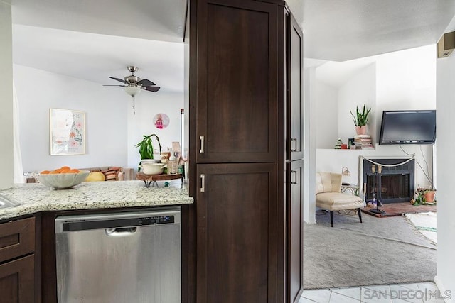 kitchen featuring dark brown cabinets, light carpet, dishwasher, ceiling fan, and light stone countertops