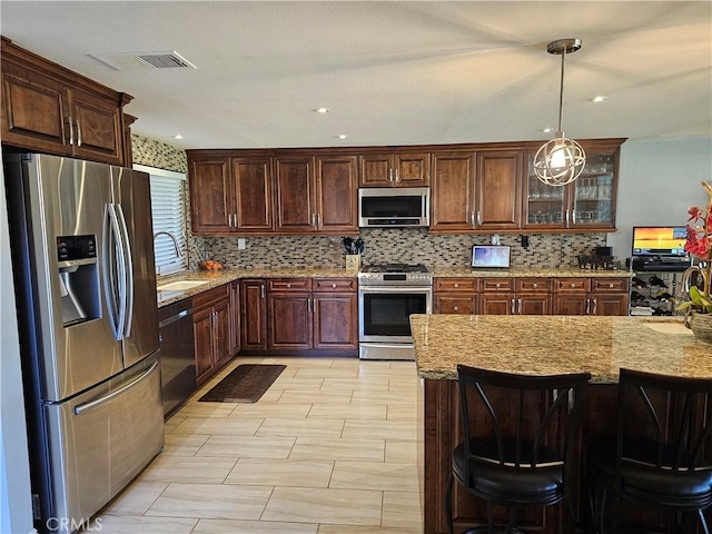 kitchen featuring pendant lighting, sink, a breakfast bar, appliances with stainless steel finishes, and backsplash